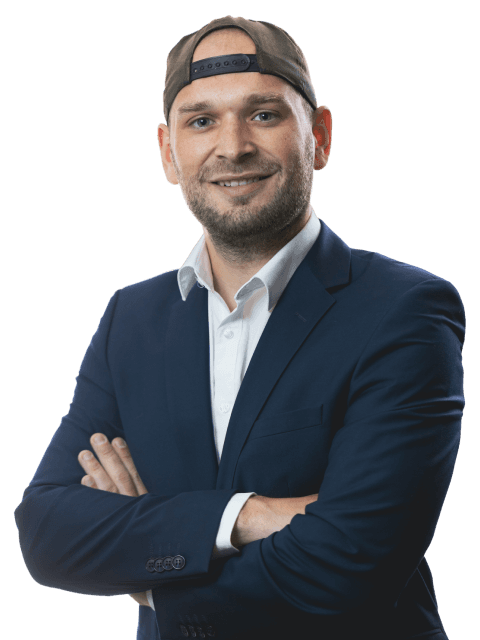 Sebastian Bader lächelnd im Anzug mit Cap und verschränkten Armen